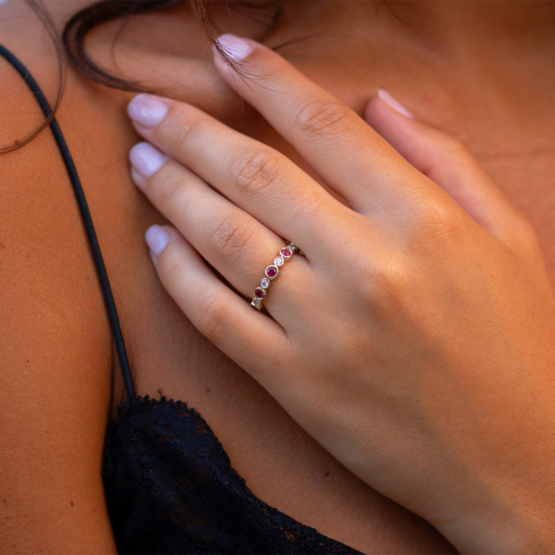 Alliance ring in roségoud bezet met afwisselende natuurlijke robijnen en diamanten in gesloten zetting, gedragen aan de vinger