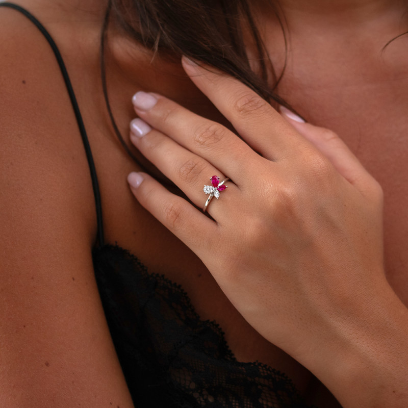 Vrouw draagt een robijn solitaire ring met natuurlijke diamanten in 18k goud, elegant bloemmotief, natuurlijke achtergrond