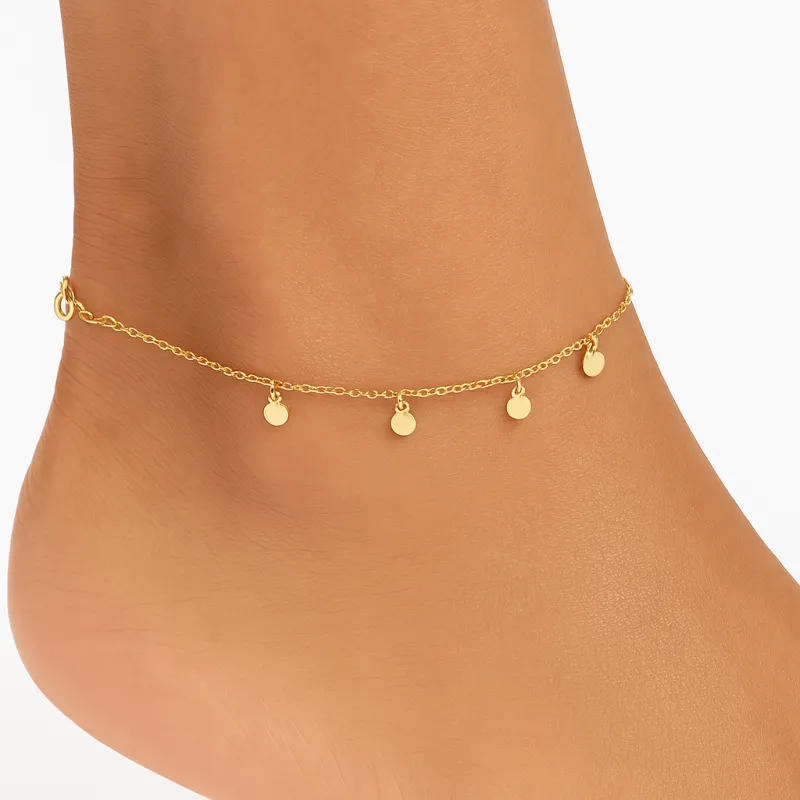 Delicate yellow gold anklet decorated with several small round pendants suspended along the chain
