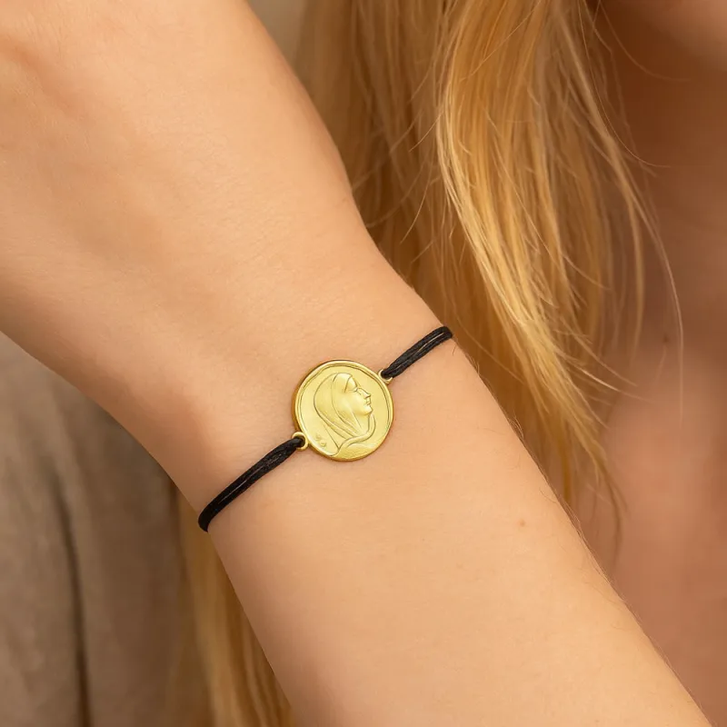 Bracelet médaille enfant en or 18 carats porté au poignet, alternative moderne et sécurisée à la chaîne de baptême traditionnelle.