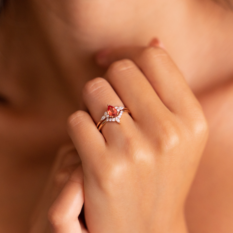 Roségold-Verlobungsring mit tropfenförmigem roten Stein, umgeben von funkelnden Diamanten