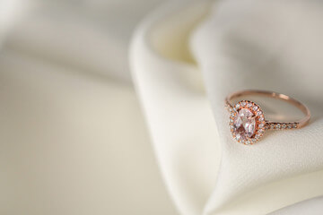 Bague en or rose avec un halo de diamant sur de la soie blanche