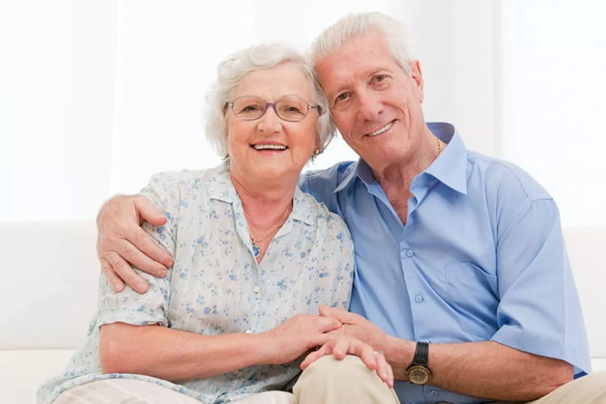 Un homme embrasse tendrement sa femme souriante tenant une tasse, symbole d’un amour complice et durable célébrant les 52 ans de mariage, les noces de tourmaline.