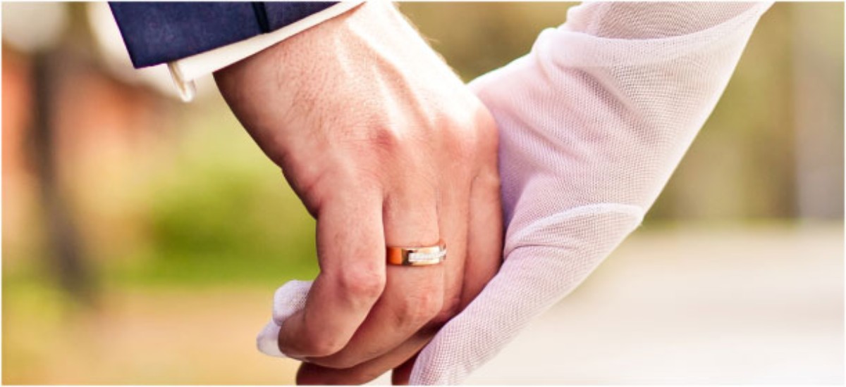 Mains enlacées portant des alliances de mariage en or jaune et blanc, design intemporel de la collection Celinni, symbole d’un amour raffiné.