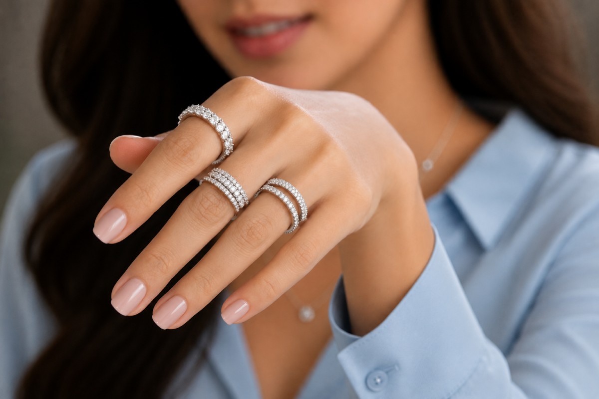 Frau trägt mehrere Diamant-Eternity-Ringe aus Weißgold mit Pavé-Fassung und runden Diamanten, die luxuriöse Eheringe stilvoll präsentieren.