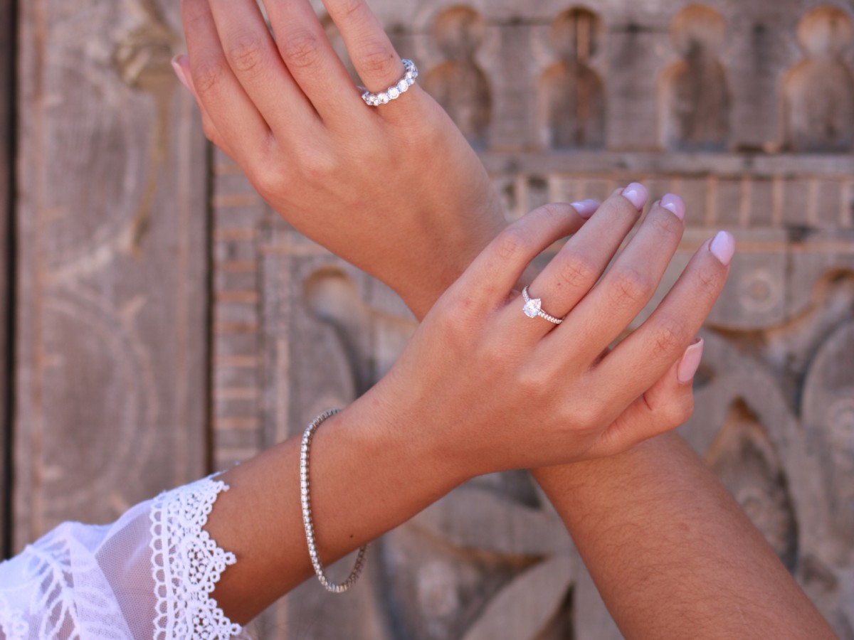 Zwei Hände mit Ringen und Armbändern aus 950er Platin, die die Eleganz der von Maison Celinni entworfenen Trauringe und Schmuckstücke zeigen.