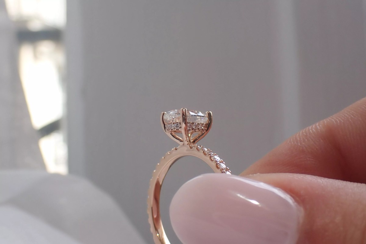 Close-up van een Celinni solitaire diamanten ring in roségoud, bezet met kleine diamanten op de ringband, benadrukt door een verfijnd en modern ontwerp.