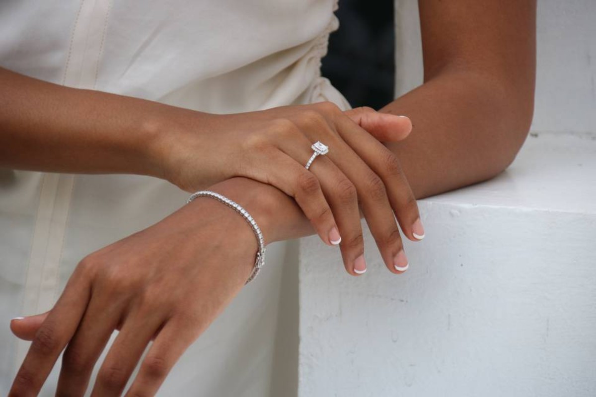 Main féminine portant une bague solitaire en diamant et un bracelet rivière en or blanc, symbole d’un cadeau de luxe raffiné et sentimental pour femme. 