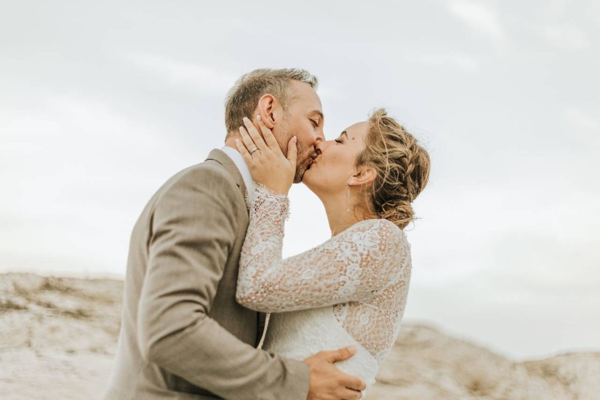 Jeunes mariés s’embrassant tendrement en pleine nature, symbole d’amour naissant et de la beauté des noces de paillettes.