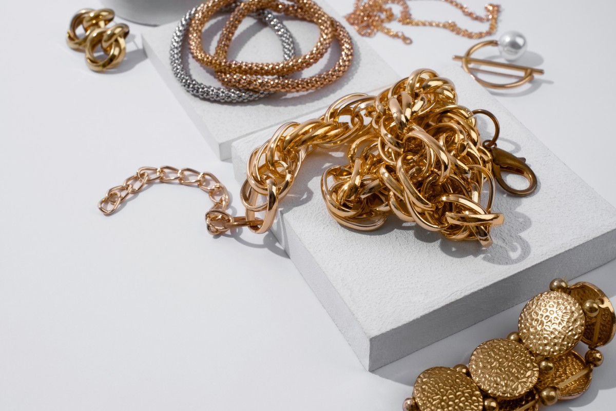 Composition de bijoux en or jaune, or rose et or blanc comprenant bracelets, chaînes et accessoires élégamment disposés, illustrant la valeur patrimoniale, la durabilité et l’élégance intemporelle de l’or en joaillerie.