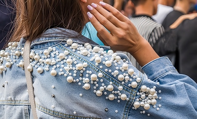 Femme élégante portant une veste subtilement ornée de bijoux.