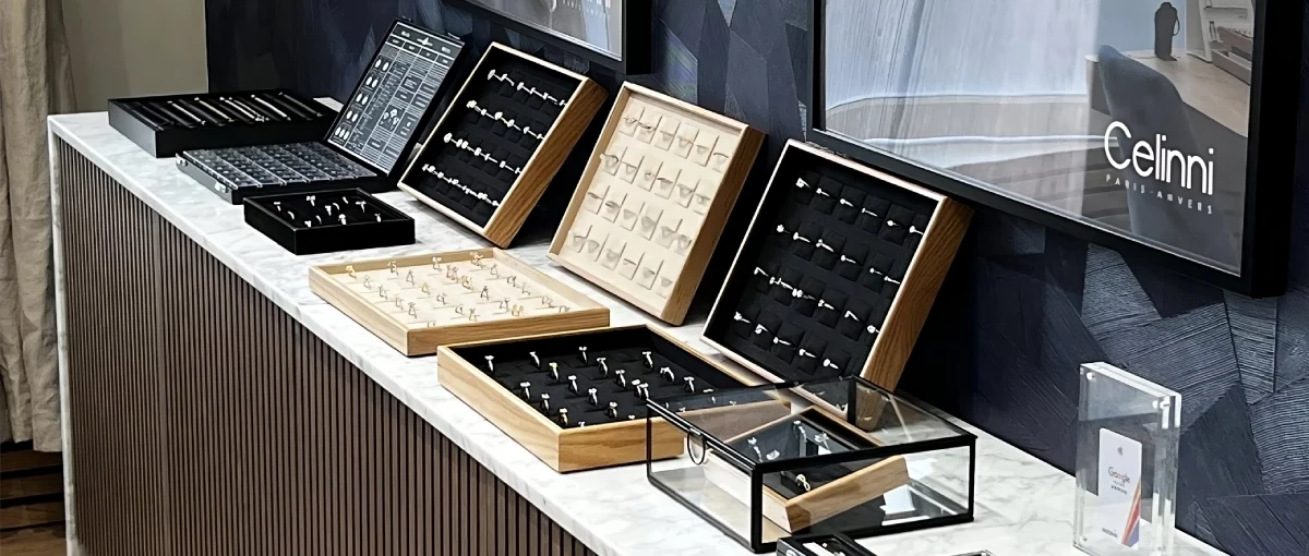 Exposition de bagues dans une bijouterie Présentoir de bagues dans une bijouterie, mettant en avant des collections variées de bijoux sertis dans des boîtes en bois et en verre.