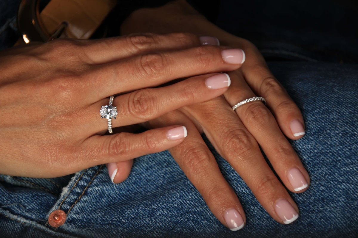 Mains élégantes portant des bagues scintillantes Vue rapprochée de deux mains avec une manucure française, portant une bague de fiançailles en diamant et une alliance en or blanc.