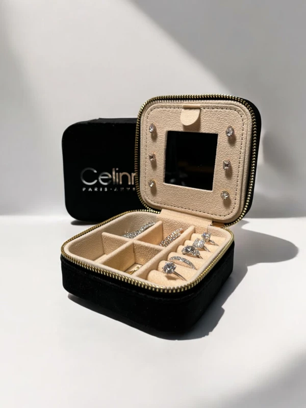 Boîte à bijoux noire Celinni ouverte, montrant des compartiments pour bagues et boucles d'oreilles avec miroir intégré.