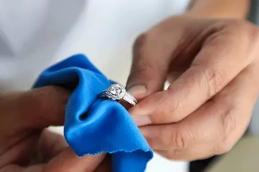 Cleaning a diamond ring with a microfiber cloth. A brilliant diamond jewelry piece is delicately cleaned with a blue cloth to preserve its shine and purity.