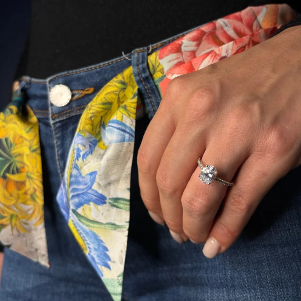 Mano llevando un anillo de diamante halo con una bufanda mini twill colorida
