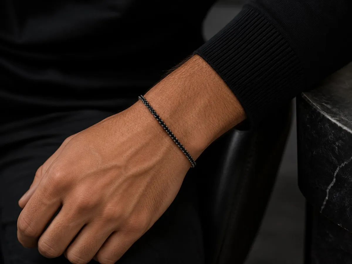 Bracelet gourmette homme en or blanc pavé de diamants noirs porté au poignet, bijou masculin élégant à porter au quotidien ou pour une occasion spéciale.