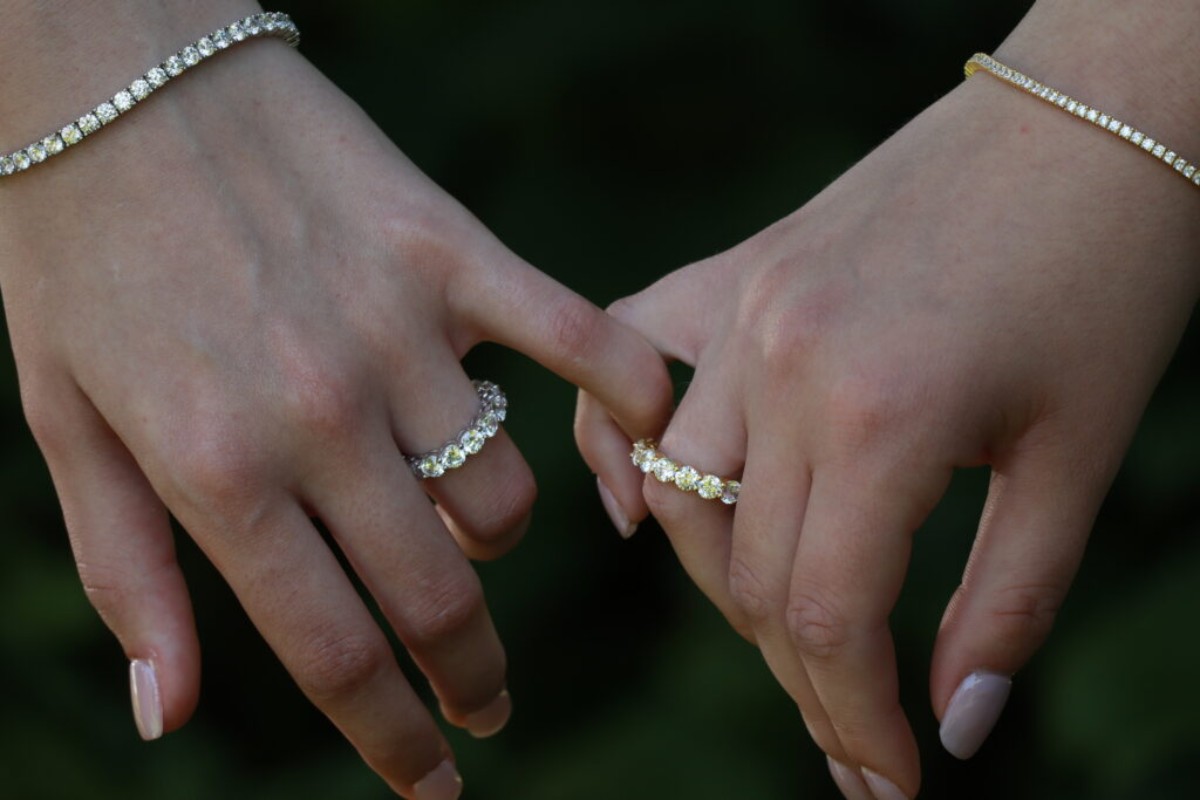 Gros plan sur deux mains portant des bracelets rivière sertis de diamants et des bagues en diamants, symboles de luxe et d’élégance féminine.