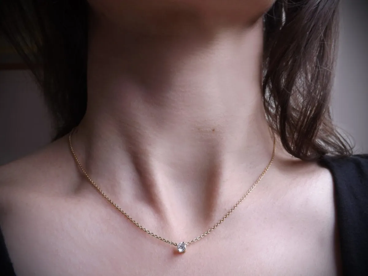 Hoe maak je een gouden ketting schoon: close-up van een fijne gouden halsketting die dagelijks wordt gedragen en stof en resten kan verzamelen.