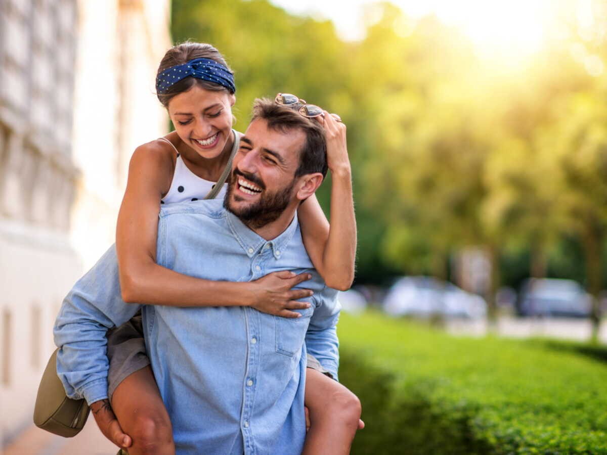 Un couple souriant profite d’un moment complice en extérieur, symbole de bonheur et de tendresse pour fêter leurs 13 ans de mariage, appelés noces de muguet.