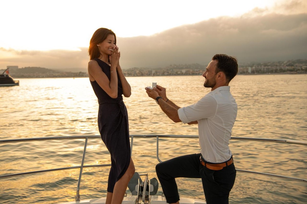 Een man doet zijn huwelijksaanzoek op een boot bij zonsondergang, terwijl de ontroerde vrouw een elegante jurk draagt. Een moderne verlovingsscène geïnspireerd op Turkse tradities.