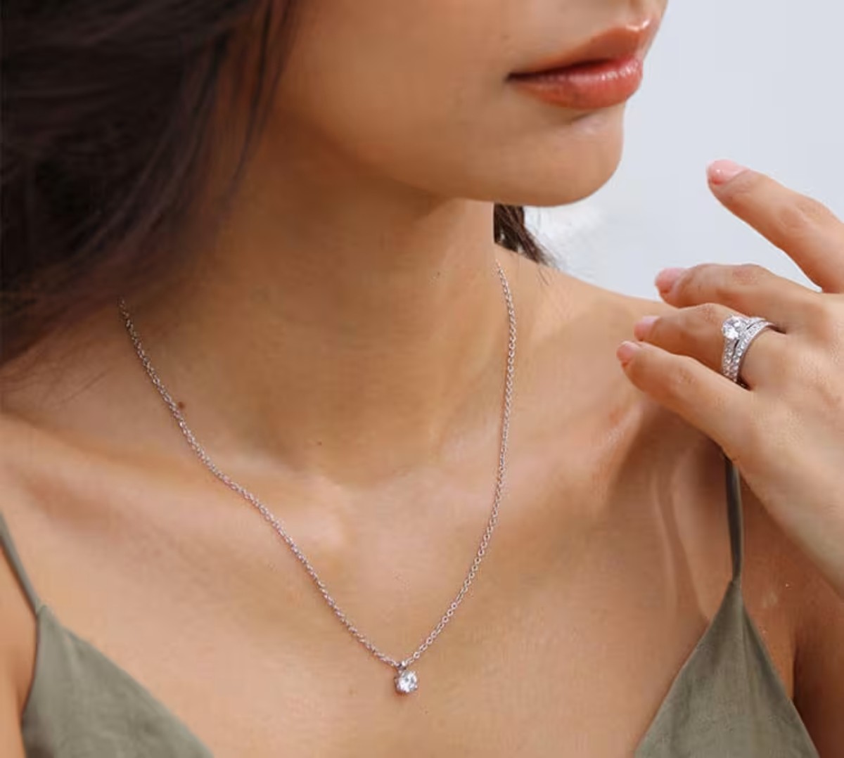 Gros plan sur une femme portant un collier en or blanc et un anneau serti de diamants Celinni, représentant l’élégance et l’amour éternel à offrir pour un anniversaire.
