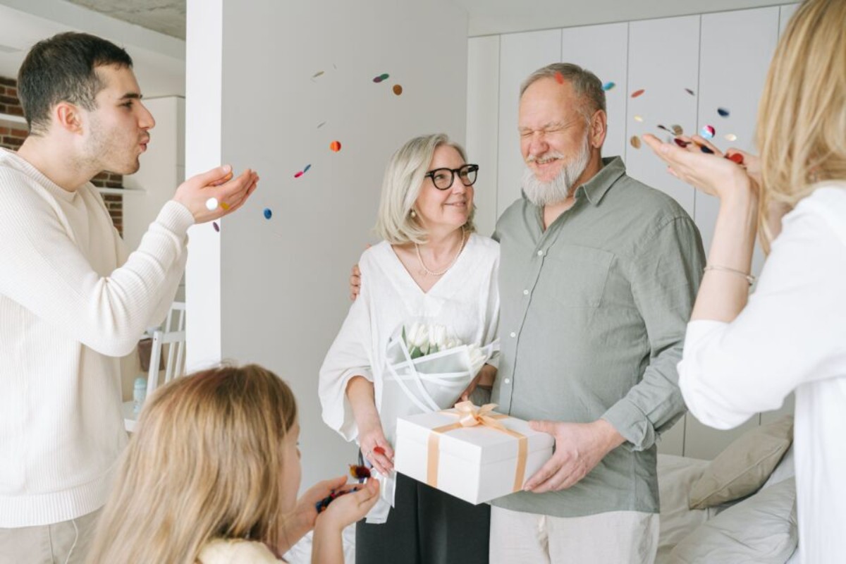 Familia celebrando los 24 años de matrimonio de una pareja, intercambio de regalos y momento cálido para un aniversario de bodas de satén.