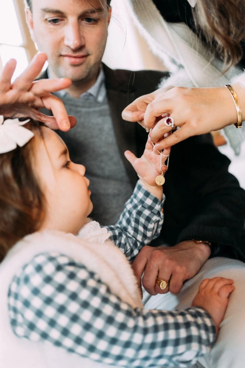 Parrain et marraine offrant une médaille de baptême en or à un enfant, bijou symbolique de protection et de transmission lors du baptême.