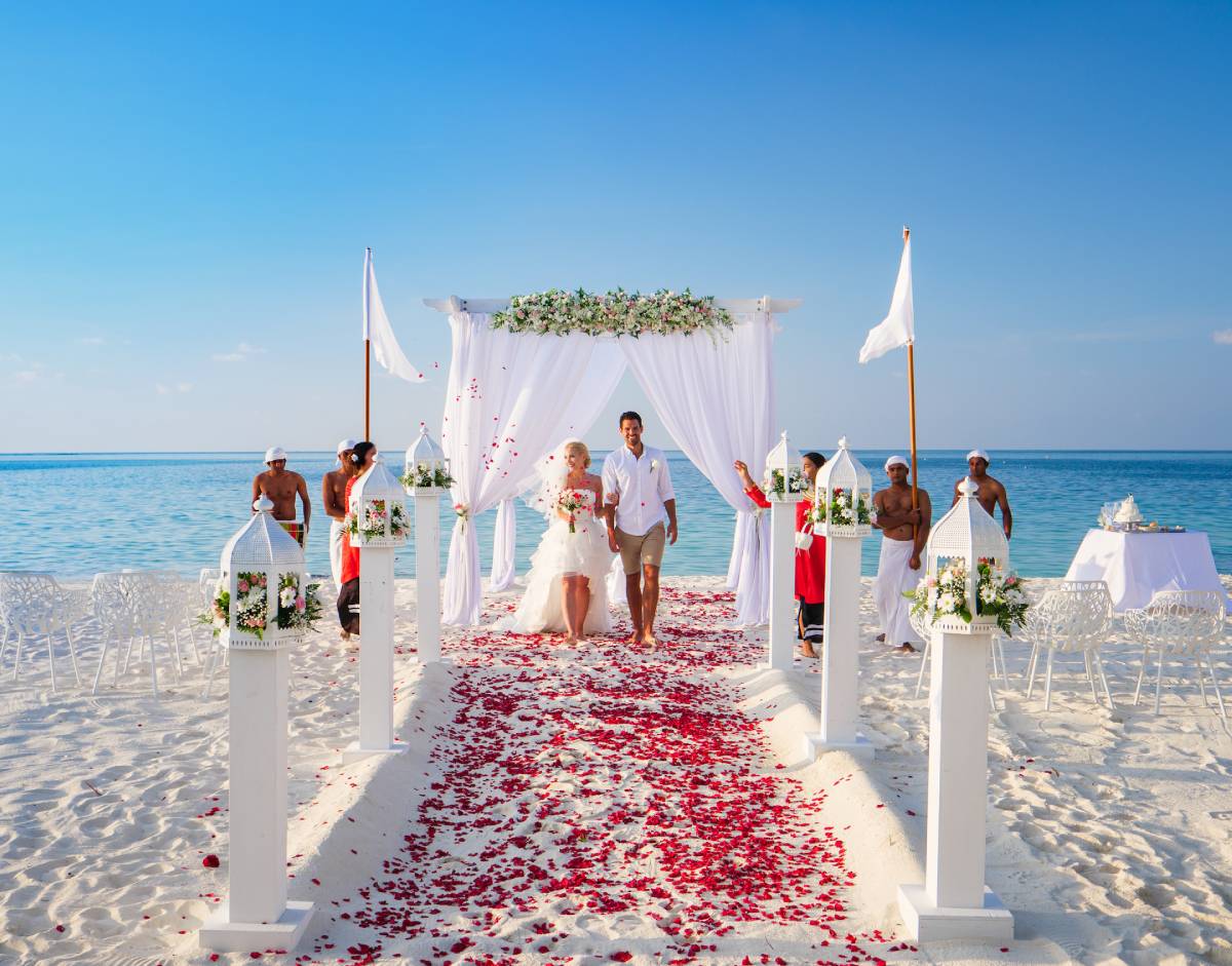 Koppel viert hun huwelijk op het strand met een met bloemen versierde loper, de ideale bestemming voor een romantische en onvergetelijke huwelijksreis.