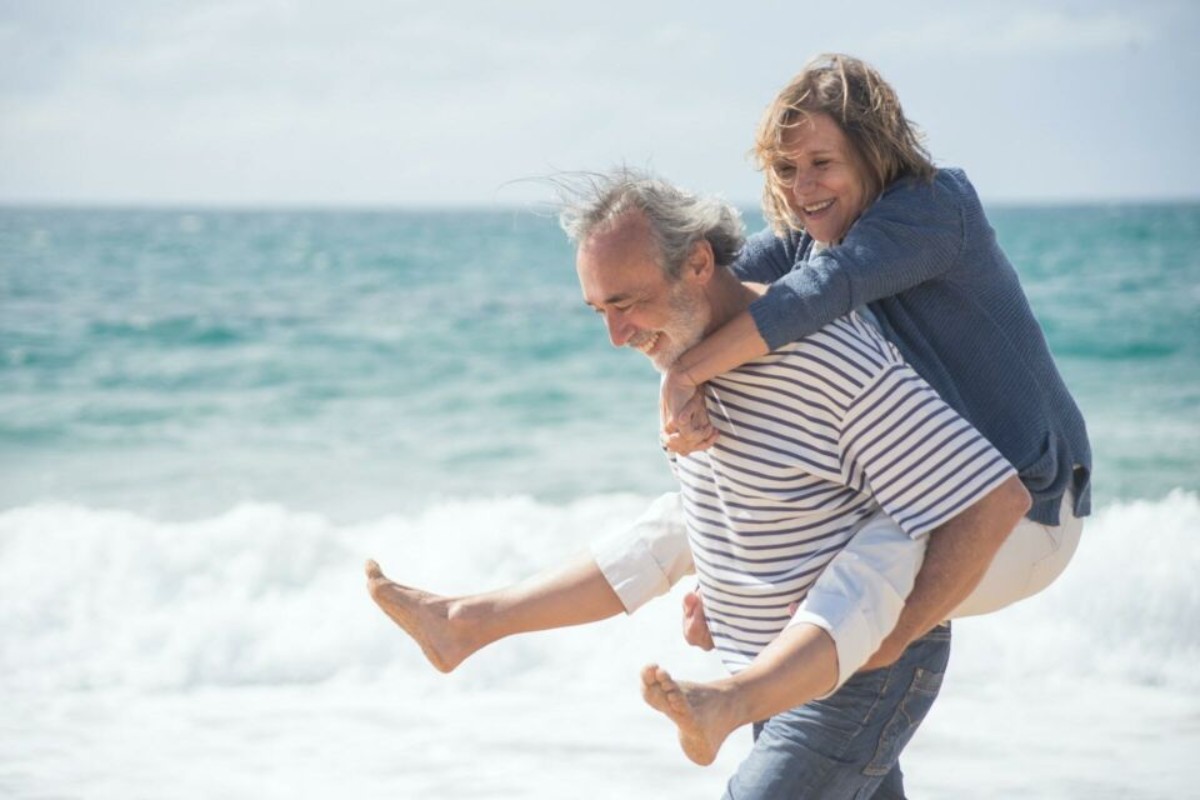 Couple marié marchant main dans la main au bord de la mer pour célébrer 27 ans de mariage et leurs noces d’acajou
