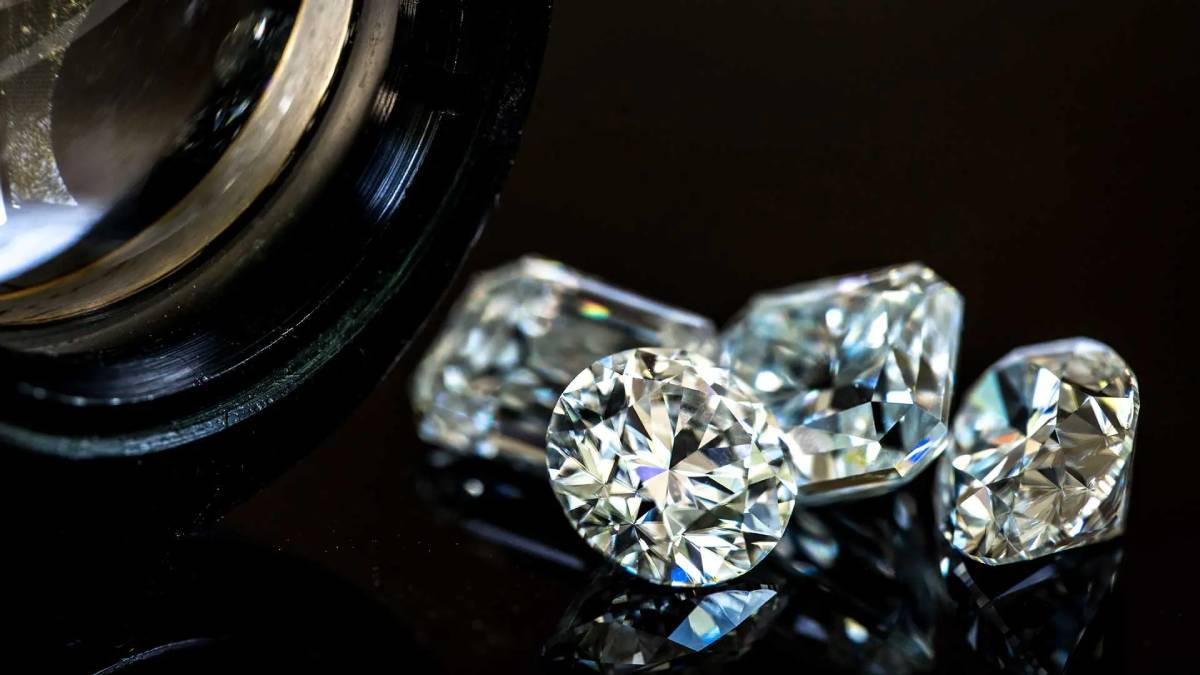 Primer plano de diamantes naturales tallados observados bajo una lupa gemológica, que muestra pureza, brillo y clasificación de los diamantes.