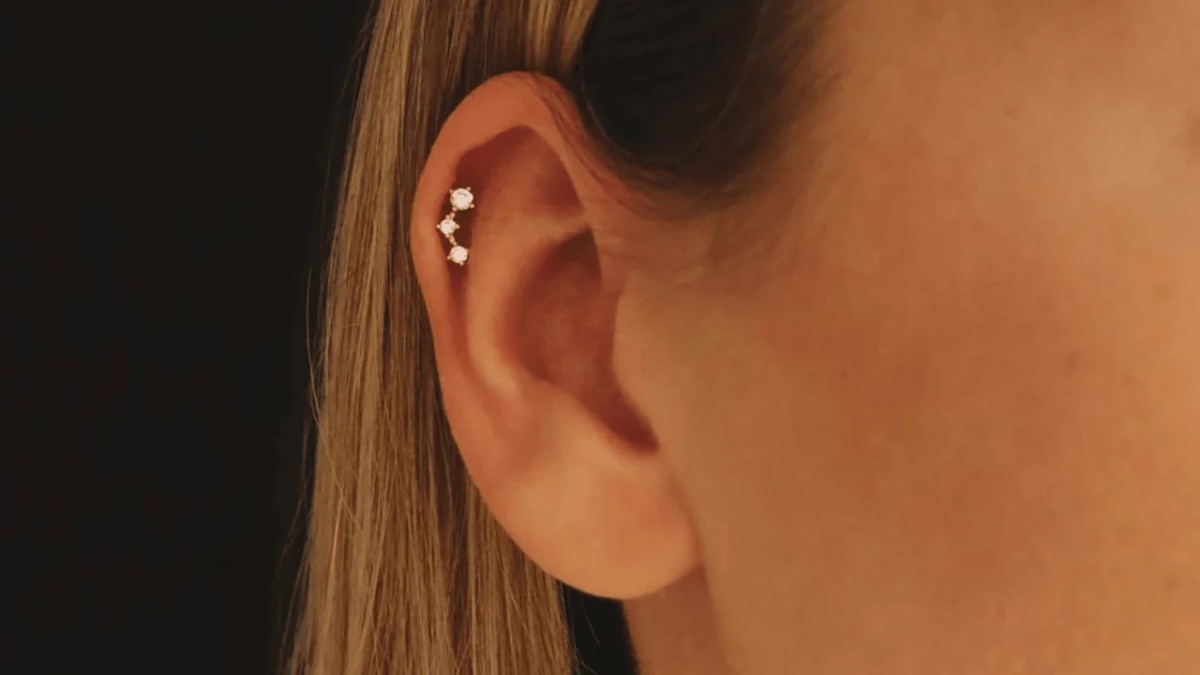 Piercing hélix au cartilage de l’oreille avec bijou en or et diamants - Celinni Gros plan sur une oreille percée avec un piercing hélix, orné de trois diamants brillants alignés dans le cartilage, illustrant élégance et style moderne.