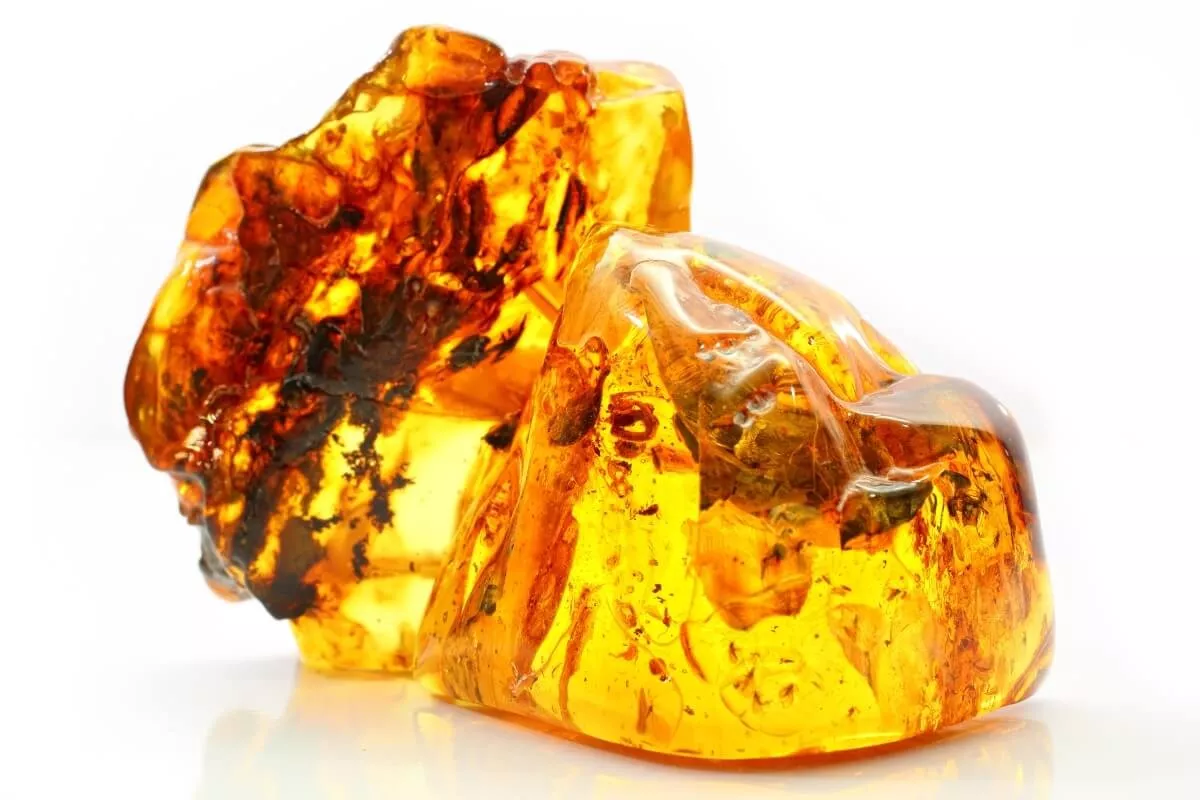 Gros plan sur deux morceaux d’ambre brut aux reflets dorés et orangés, illustrant la chaleur, la protection et la longévité associées aux noces d’ambre célébrées pour 34 ans de mariage.