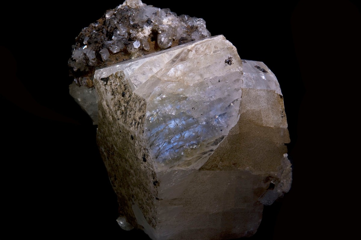Rohmondstein mit perlmuttartigen und bläulichen Reflexen, der seine charakteristische Adulareszenz und natürliche Kristallisation hervorhebt.