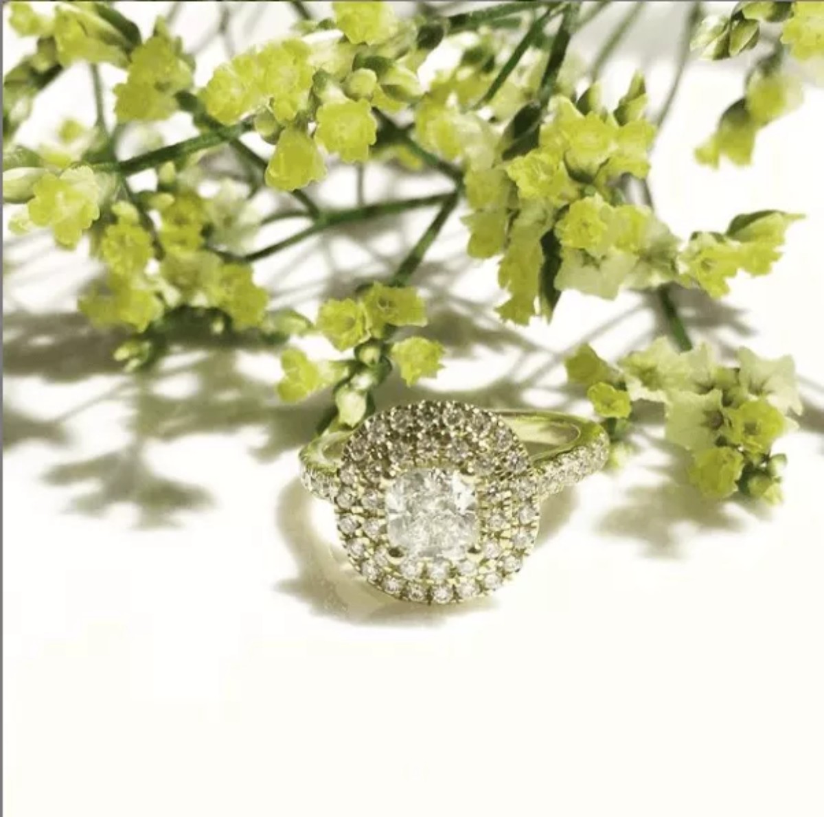 Diamond engagement ring elegantly displayed among white flowers and green foliage, illustrating fine diamond jewelry at Celinni in Lyon.