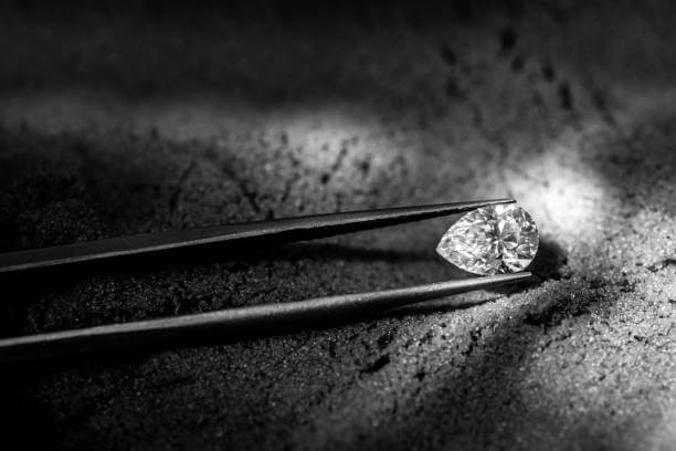 Diamant taille poire taillé et qui scintille avec un pince gemmologie