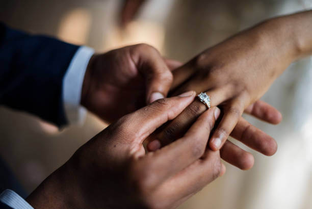 Passando o anel no dedo da mulher durante o pedido de noivado